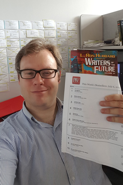 Auston holding up the Publishers Weekly Bestseller list for Writers of the Future Vol 31