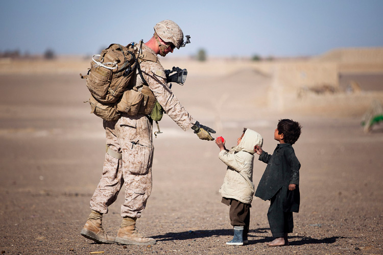 Small kids handing soldier a ball